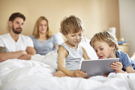 父母床上的男孩使用数字平板电脑