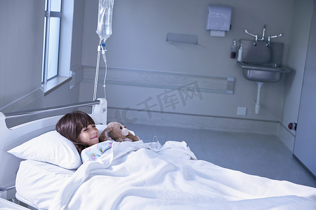 病床上的女病人抱着医院儿科病房的玩具兔