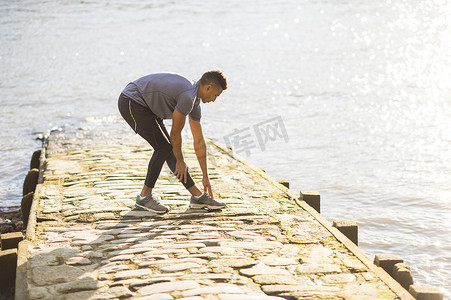 运动袜摄影照片_一名男子在英国伦敦沃平的码头上伸展身体