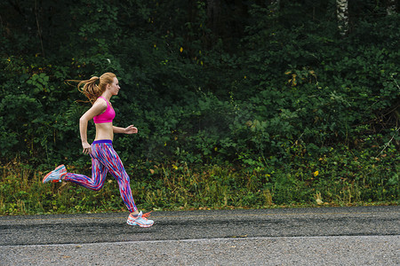 公路奔跑摄影照片_十几岁的女孩沿着乡村公路奔跑