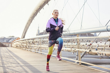 中年女子跑步者在城市人行桥上快速奔跑