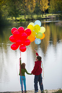 抱着玫瑰花摄影照片_兄妹俩在公园里抱着一串串气球
