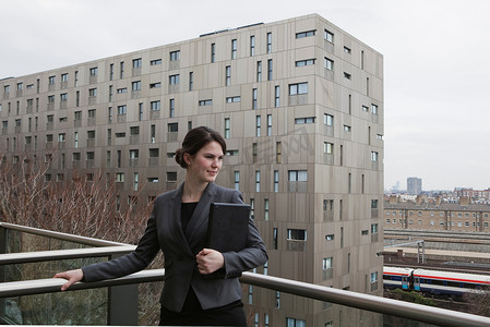 无线力量摄影照片_一名妇女站在阳台上拿着笔记本电脑