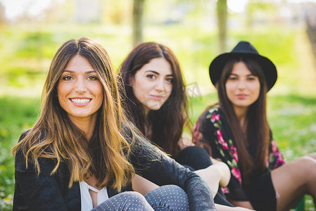 三位年轻女性朋友坐在公园里的肖像