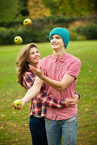 十分之三摄影照片_一对十几岁的夫妇在公园里玩苹果