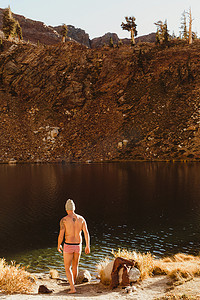 男性徒步旅行者穿着泳裤在湖边晒脸矿泉王美国加利福尼亚州红杉国家公园