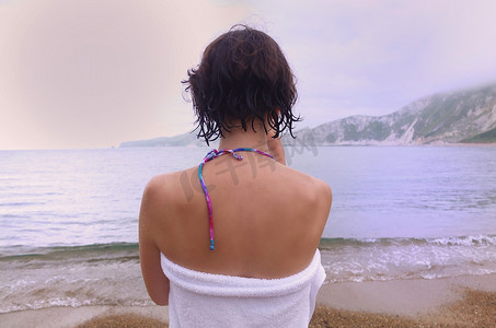 短发少女摄影照片_海滩上裹着毛巾的女人