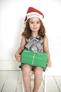 戴着圣诞帽的女孩腿上放着圣诞礼物