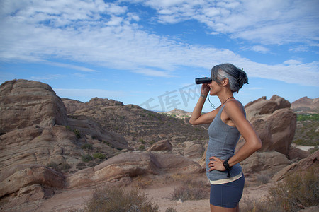 投用摄影照片_站在巴斯克斯岩石边用双筒望远镜看的女人