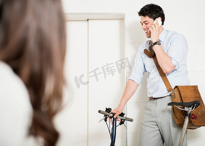 骑着自行车坐电梯打手机的男人