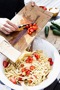 一名妇女用刀把西红柿刮到碗里