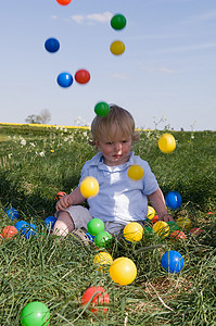 坐在球上的男孩摄影照片_蹒跚学步的孩子玩彩色球