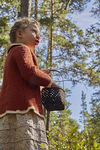 森林里带着篮子的穿着复古服装的女孩