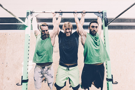 三名男子交叉训练者在健身房的健身杆上训练