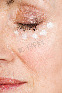 皮肤老化摄影照片_涂眼霜的女人