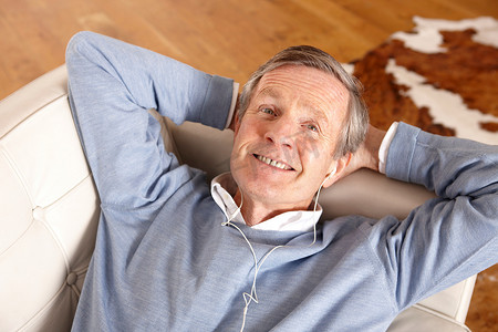 坐在沙发上听耳机的老人