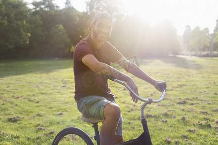 阳光明媚的公园里骑自行车的年轻人的肖像