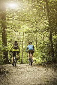 成熟的山地自行车夫妇在森林小径上骑自行车的后景
