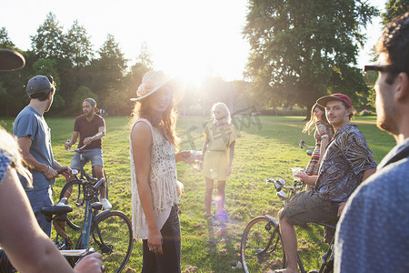 日落时分一群参加派对的成年人骑着自行车抵达公园