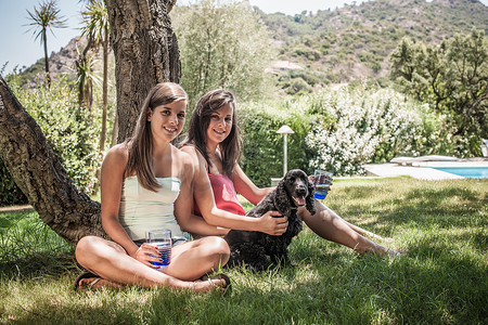 意大利撒丁岛卡波特拉假日家庭花园里两个带着狗的女性朋友的肖像