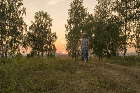 日落时分妇女沿着乡村土路奔跑的背影