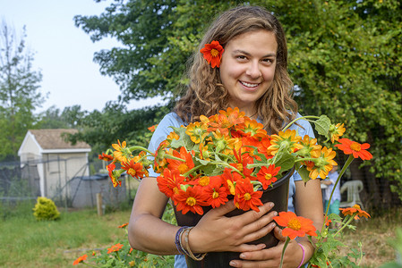 鲜花鲜摄影照片_农场女工手持一桶鲜切花的肖像