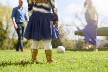 一群人踢足球摄影照片_小女孩在花园里和家人一起踢足球