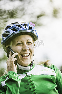 德国巴伐利亚州奥格斯堡年轻女性骑车人在智能手机上嬉笑聊天