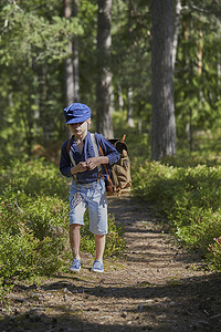 背着背包穿着复古服装的男孩走在森林里