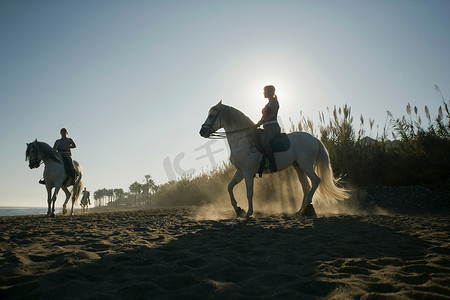女子骑马摄影照片_三名女子在海滩上骑马