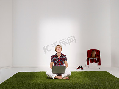 一名妇女拿着笔记本电脑坐在草地上