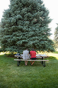 一对十几岁的情侣在公园的野餐桌上学习后景
