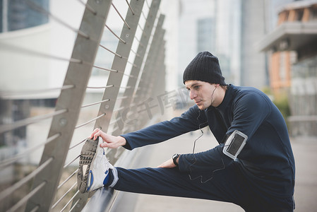 热身游戏摄影照片_年轻男子跑步者在城市人行桥上热身
