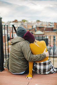 坐在城市屋顶露台上眺望的年轻夫妇