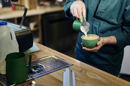 咖啡店男咖啡师将牛奶倒入咖啡杯的剪影