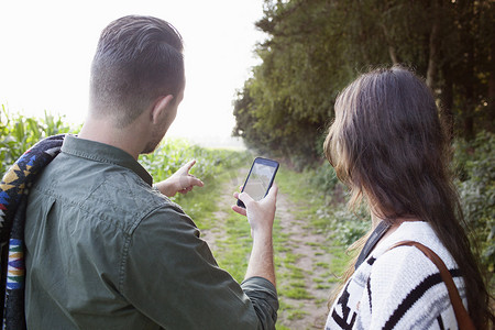 情侣在野外用智能手机导航的肩上视角