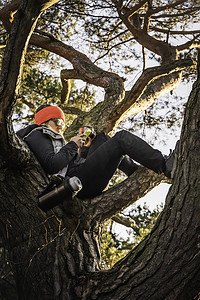 德国巴伐利亚州奥格斯堡一名妇女在树梢上放松和使用手机