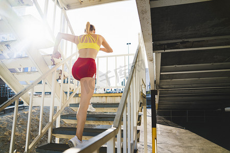年轻女子在城市环境中锻炼跑上楼梯后视