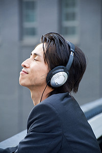 一名中年商人在城市屋顶上戴着耳机听音乐