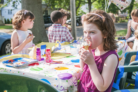 动物幼儿园摄影照片_小女孩在幼儿园聚会上吃冰激凌
