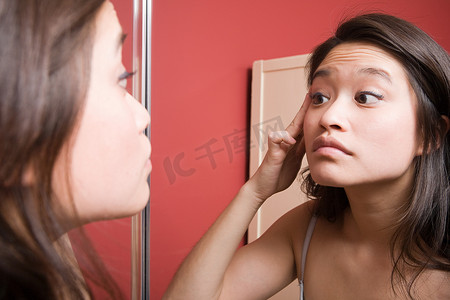 护肤摄影照片_看着镜子里的镜子的年轻女子