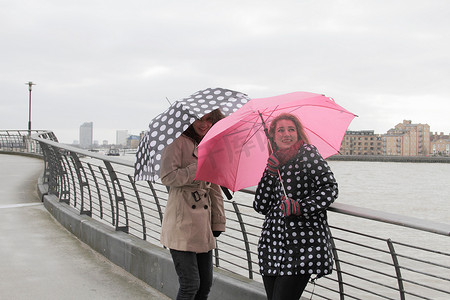 少女撑着雨伞摄影照片_河边两名撑着雨伞的年轻女子