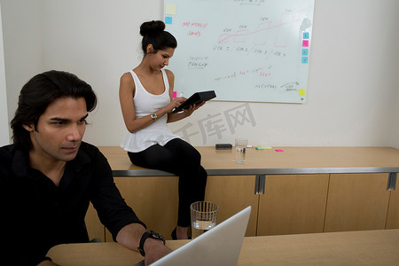 创意背景场摄影照片_年轻男子与女子为背景使用笔记本电脑