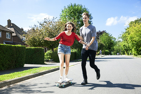 爱情发生摄影照片_年轻夫妇在滑板上练习