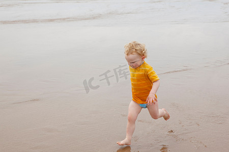 海滩上的男孩在波浪中奔跑