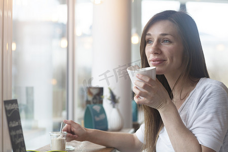 年轻女子透过咖啡馆的窗户凝视着外面