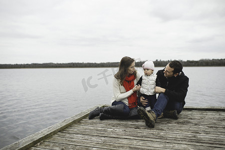 年轻的一家人坐在码头上