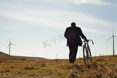 一名男子拉着自行车上山向风电场驶去