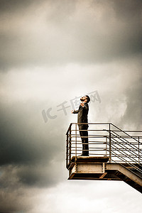 手机侧视图插画摄影照片_中年男子身着西装双臂张开头向后仰站在楼梯上的低角度侧视