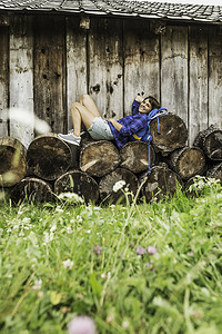 一名妇女坐在一堆砍下的原木上休息